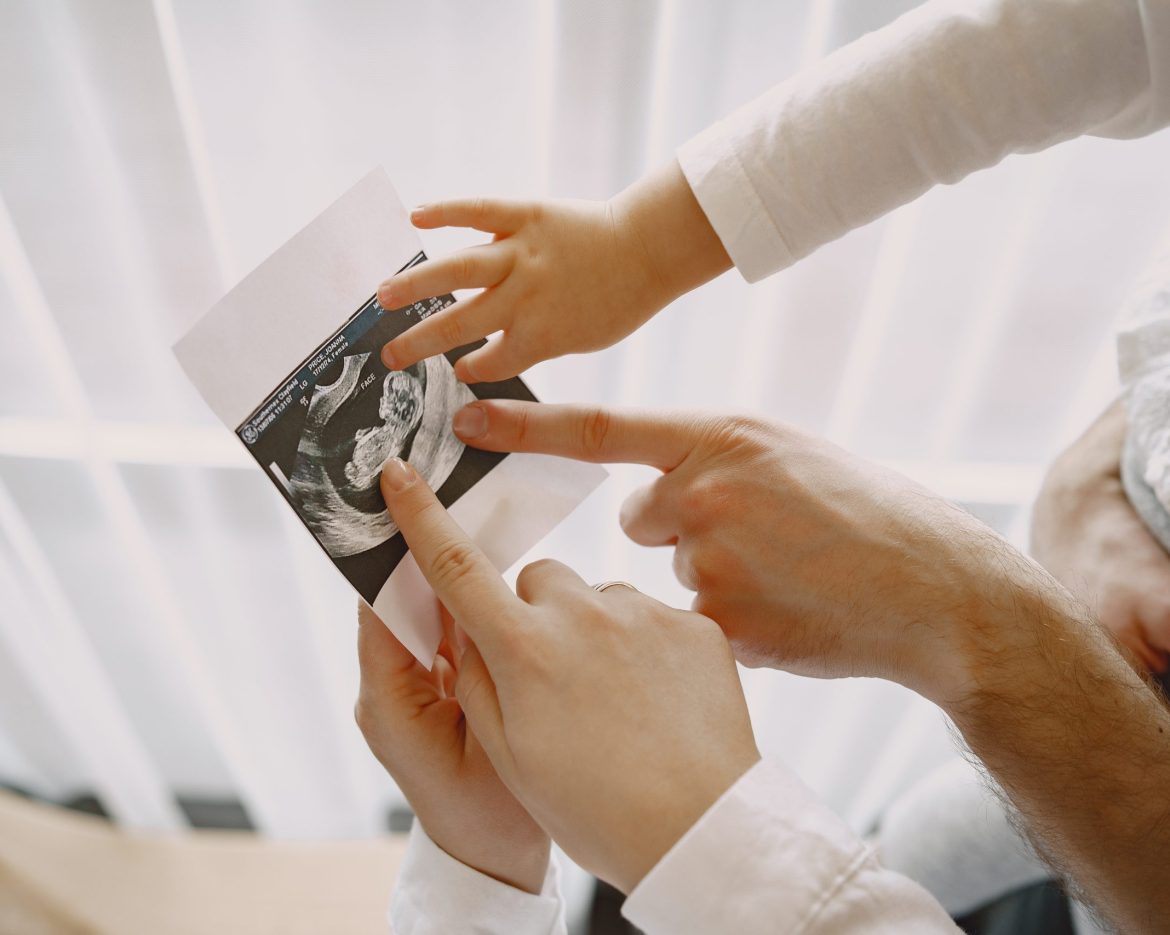 Pregnant mom dad and little daughter look at photo