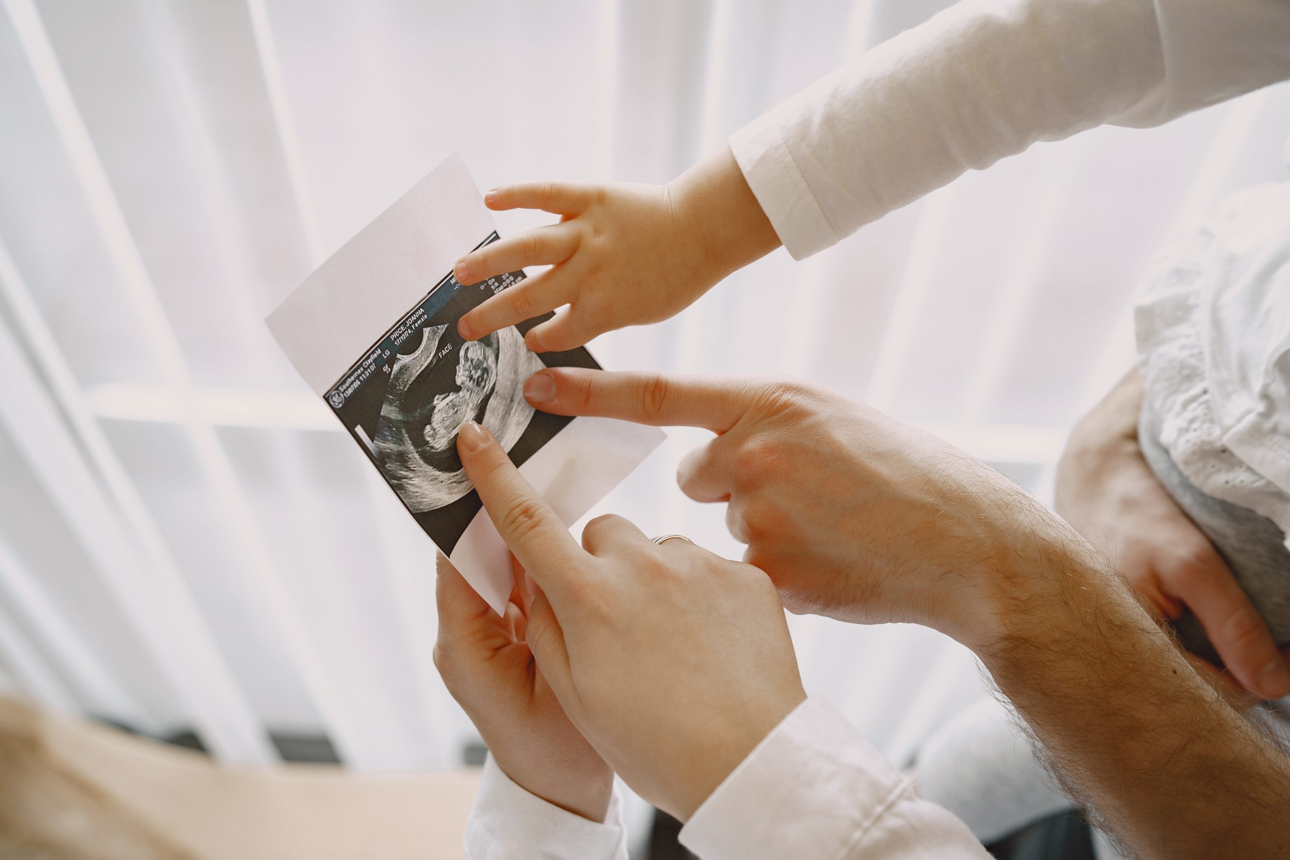 Pregnant mom dad and little daughter look at photo