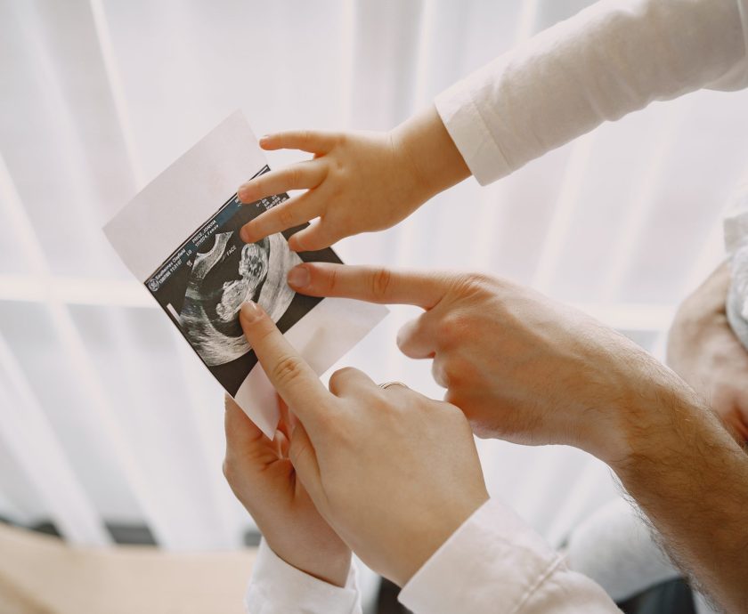 Pregnant mom dad and little daughter look at photo