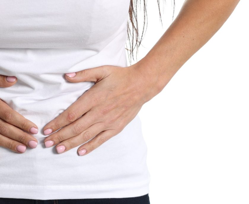 Young woman holding on to sore belly closeup